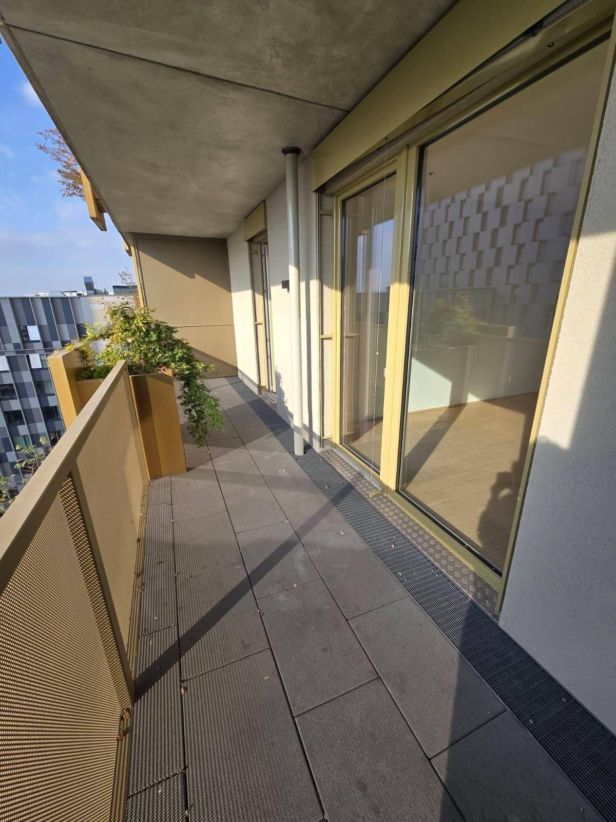 Langer, schmaler Balkon mit Fliesenboden und Blick auf die Stadt und die umliegenden Gebäude.