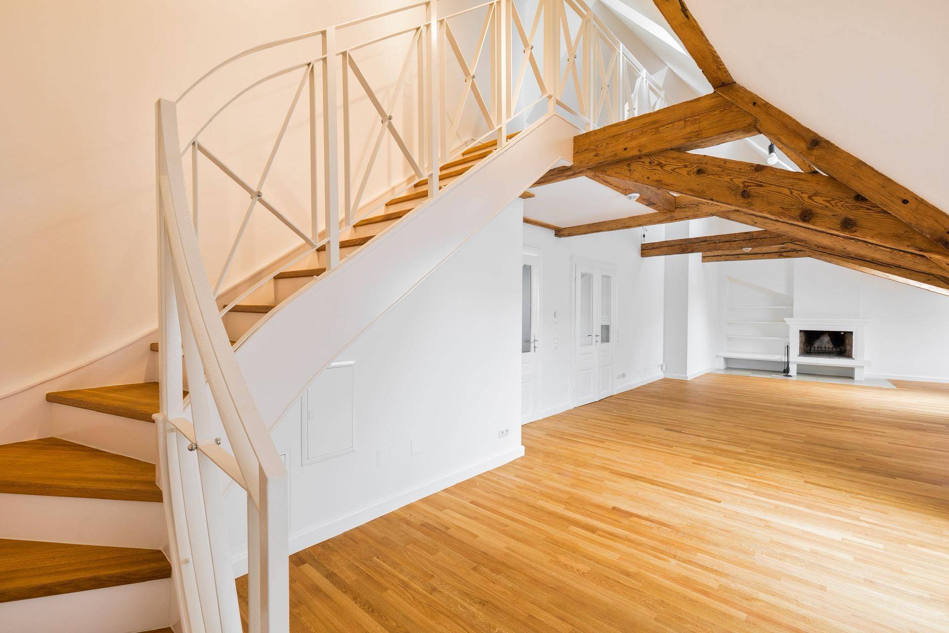 Elegante weiße Treppe mit Holzstufen, die zum offenen Dachgeschoss führt.