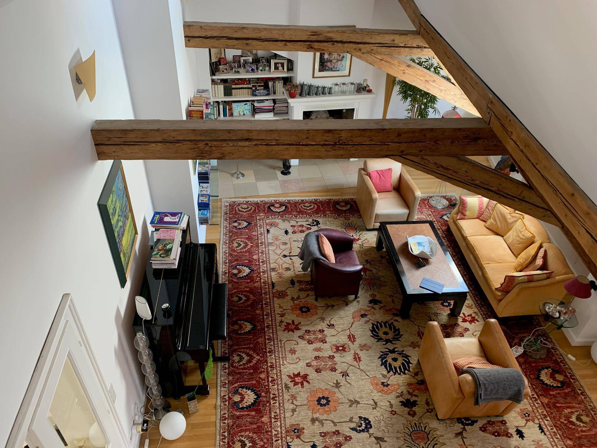 Gemütlicher Wohnbereich mit Klavier, Sofas und einem großen Teppich, von oben betrachtet.