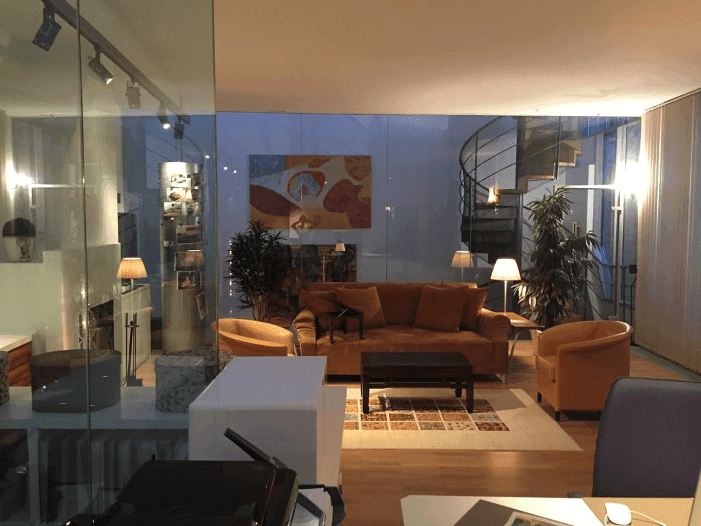 Gemütlicher Wohnbereich mit Sofas, Parkettboden und moderner Glasabtrennung.