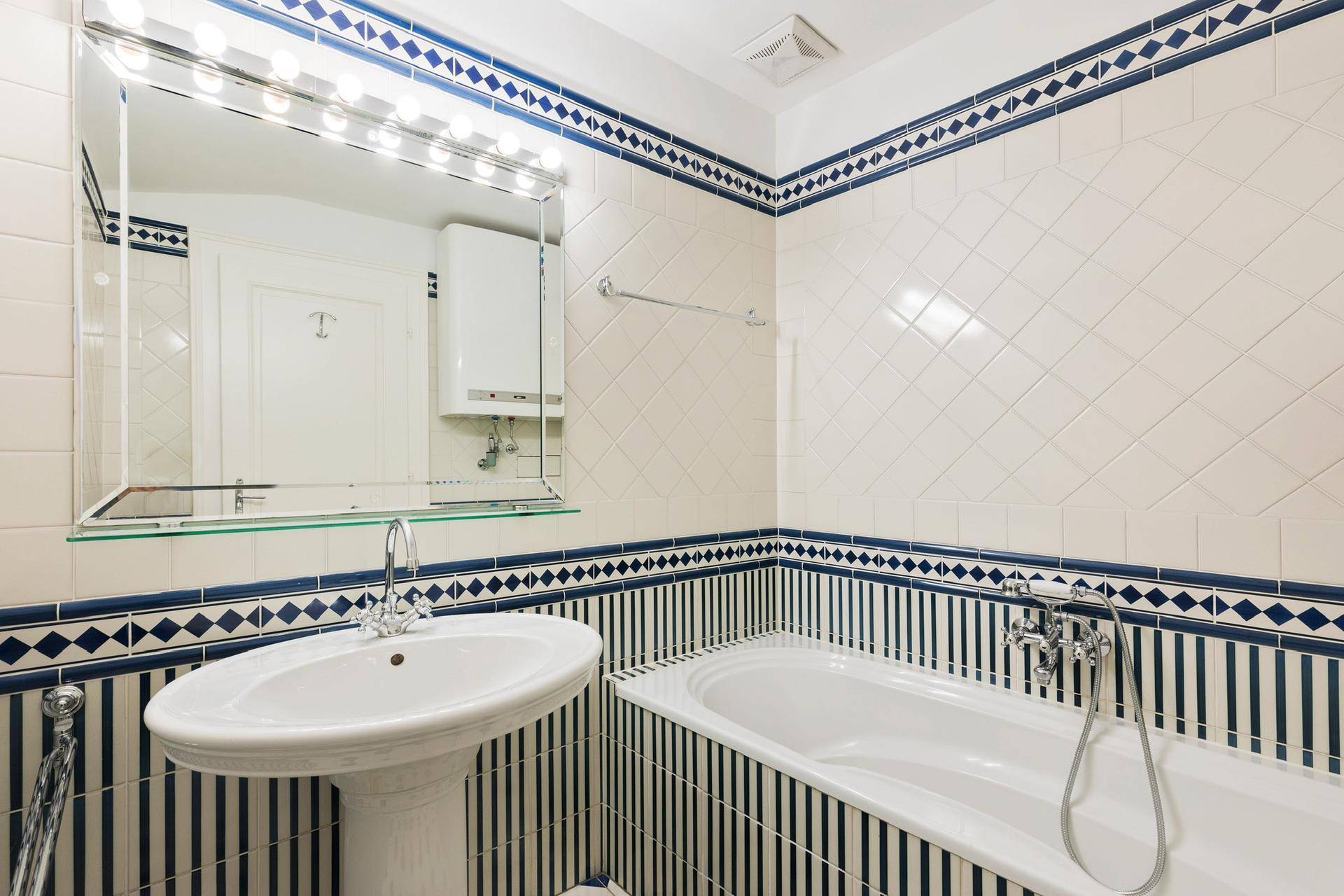 Badezimmer mit Badewanne, Waschbecken und dekorativen blau-weißen Fliesen.