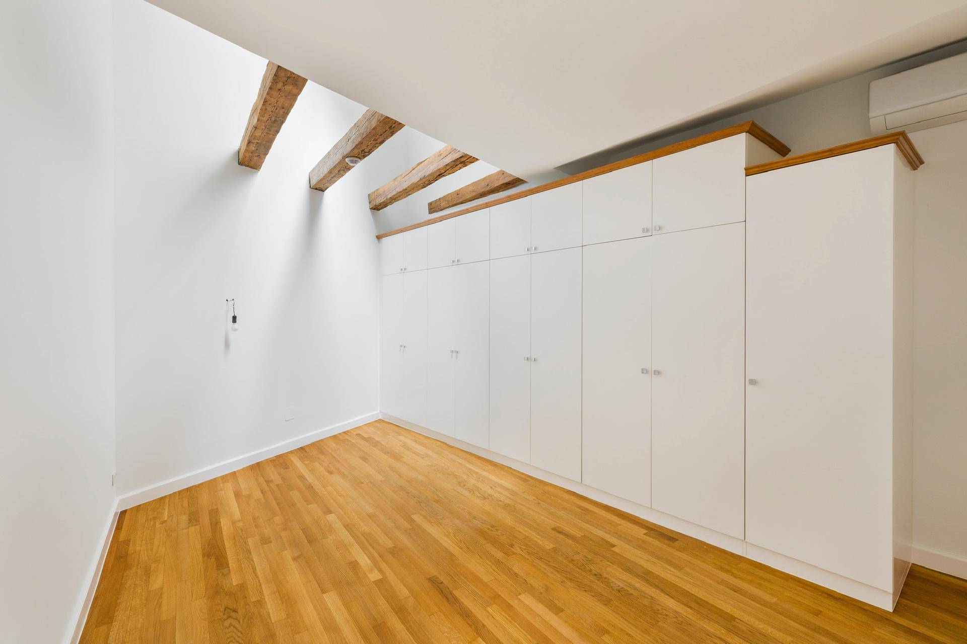 Geräumiges Zimmer mit Einbauschränken, Holzbalken und viel Tageslicht.