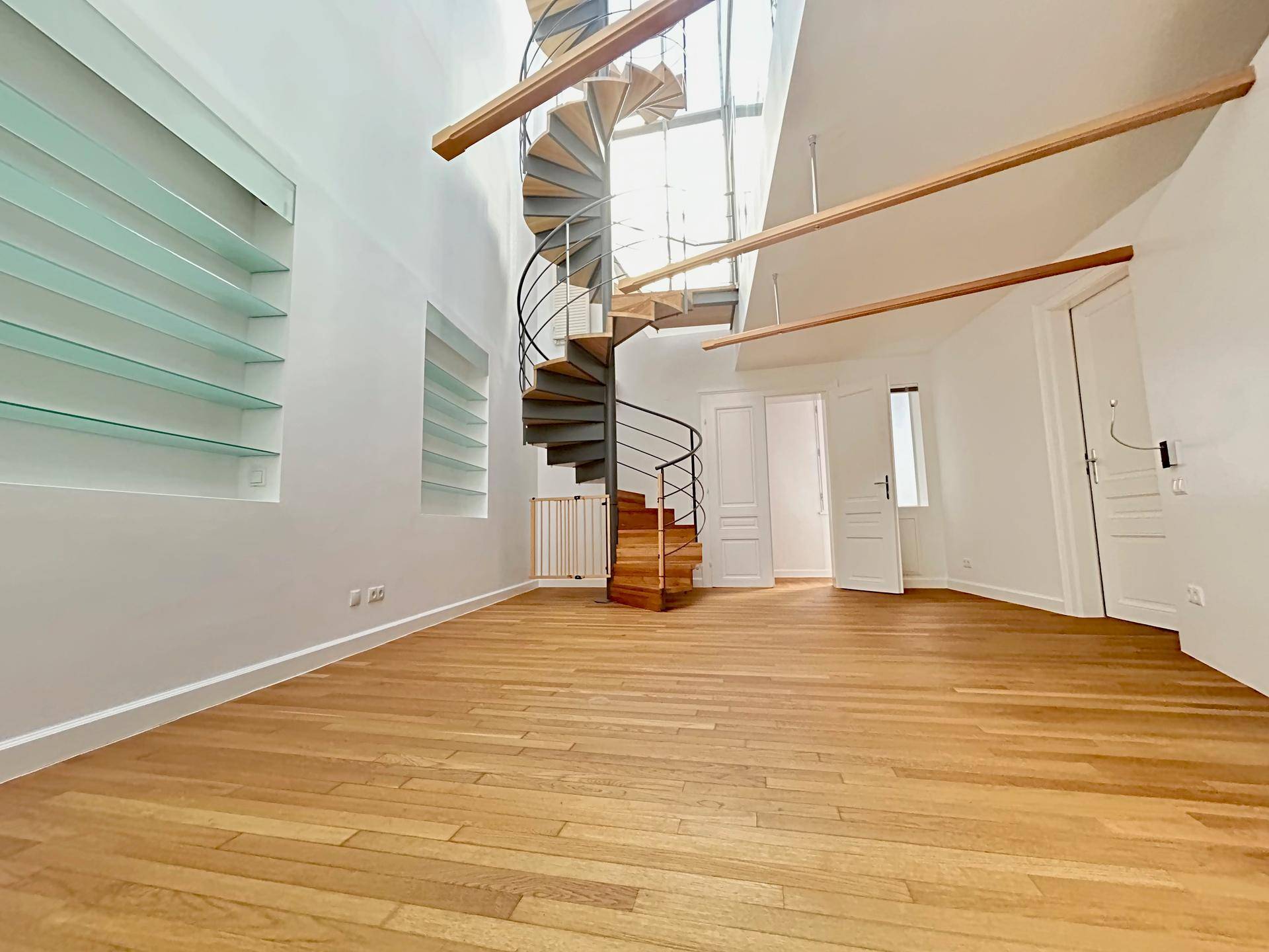 Heller Wohnbereich mit Holzparkett, Wendeltreppe und hohen Decken.