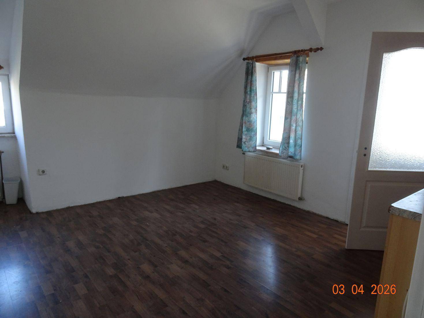 Heller Raum mit Laminatboden und Dachschräge, der vielseitig genutzt werden kann.