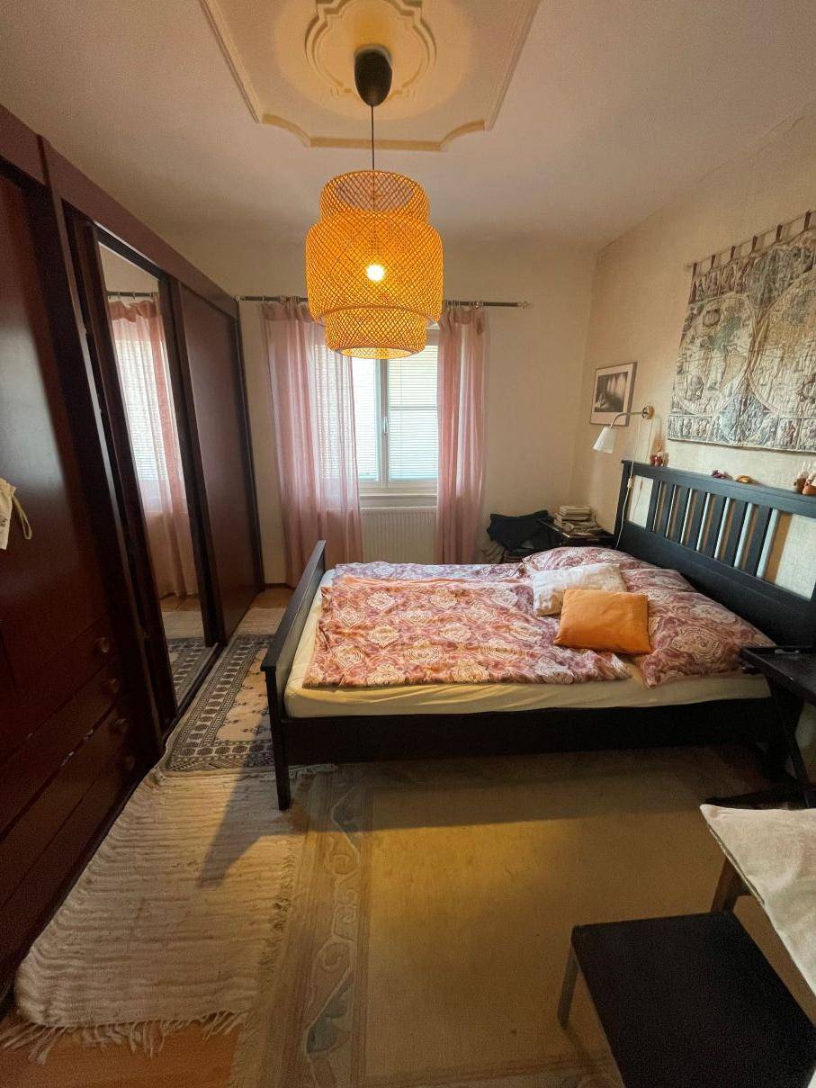 Schlafzimmer mit Doppelbett, großem Spiegelschrank und dekorativer Deckenrosette.