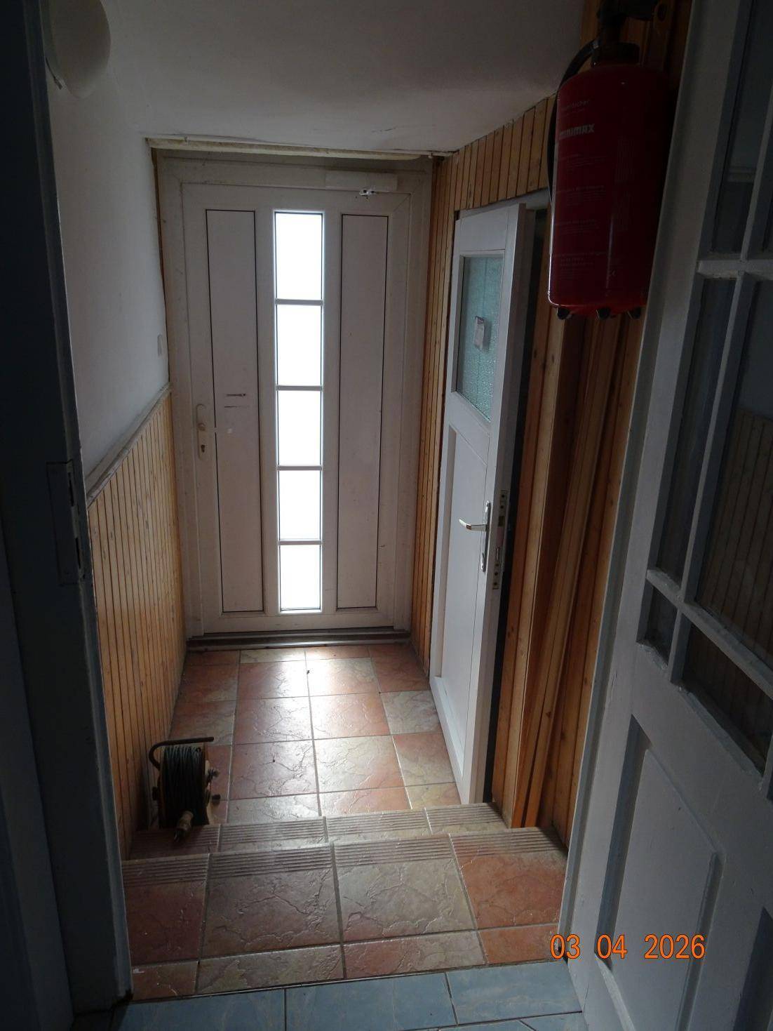 Heller Eingangsbereich mit gefliestem Boden und Holzvertäfelung an den Wänden.