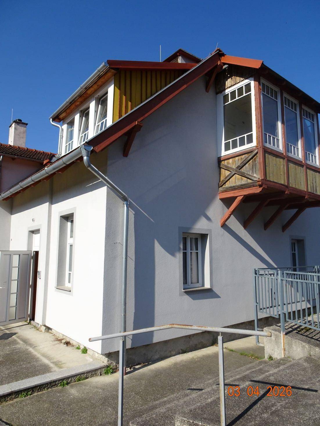 Seitenansicht des Hauses mit Eingangsbereich und einem verglasten Erker im Obergeschoss.
