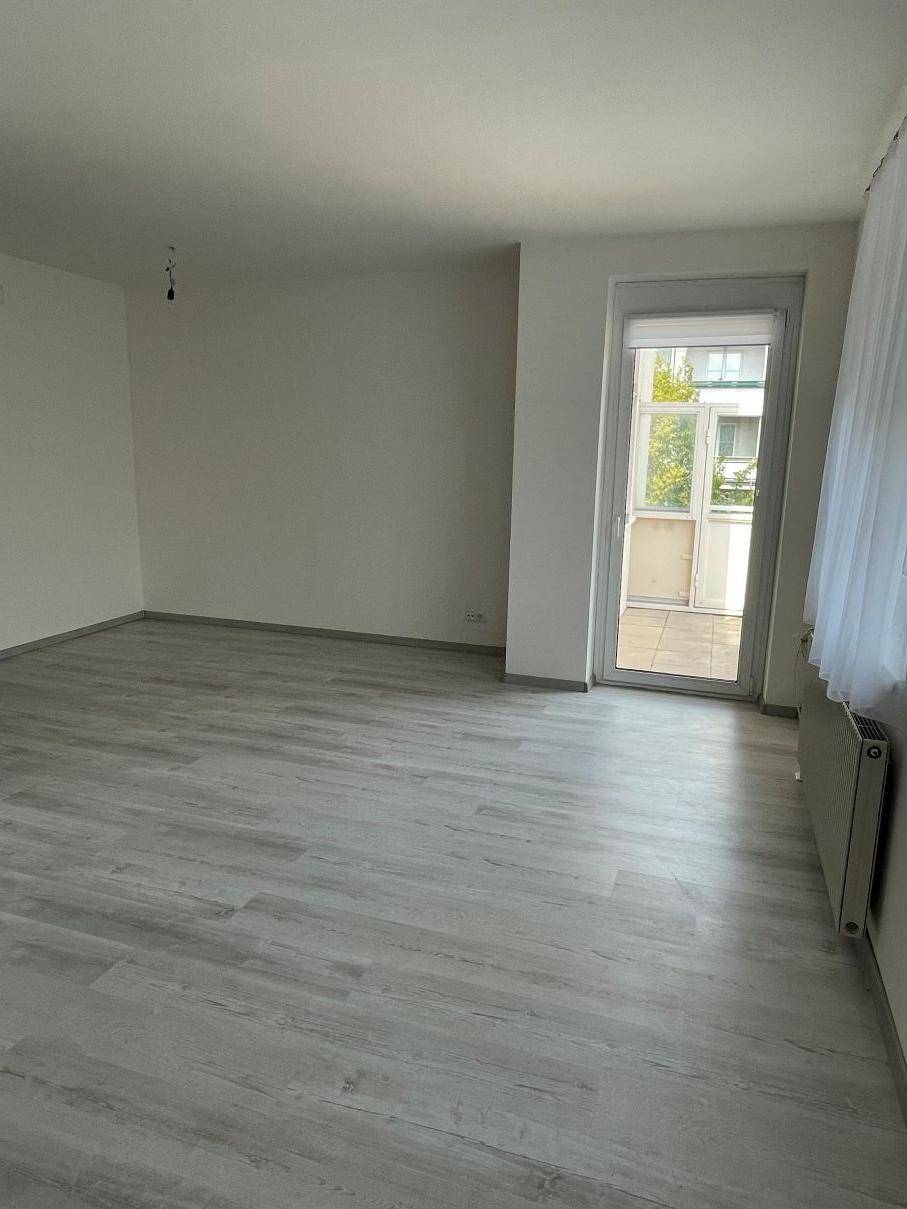 Heller Wohnbereich mit Laminatboden und direktem Zugang zu einem Balkon.
