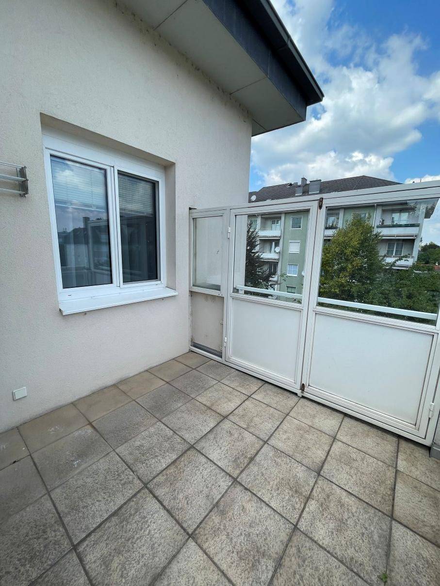 Balkon mit Fliesenboden und Blick auf die umliegenden Gebäude.