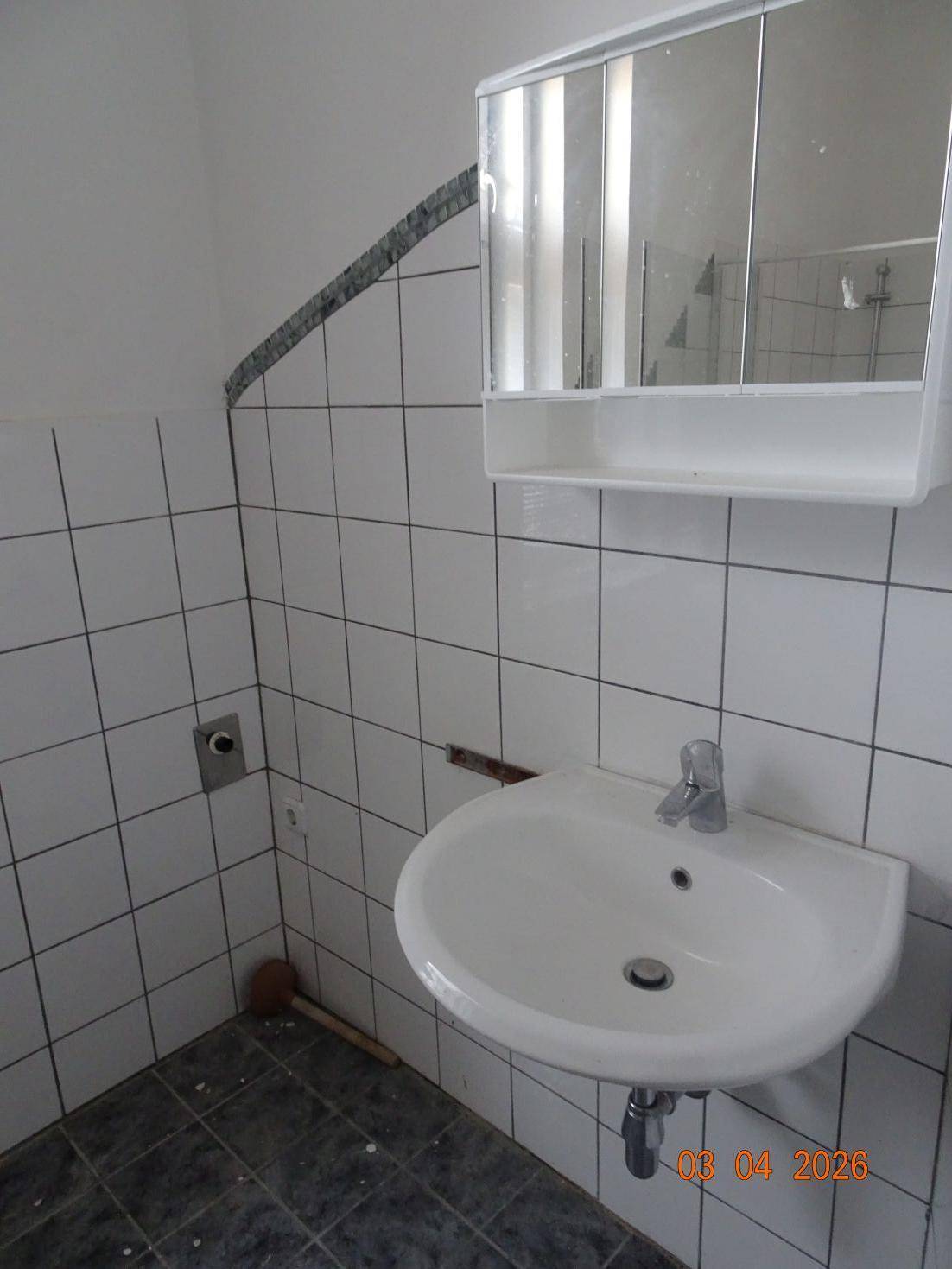 Badezimmer mit Waschbecken, Spiegelschrank und weißen Wandfliesen.