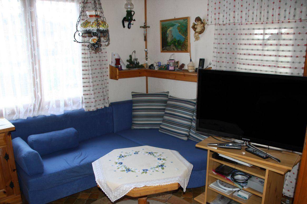 Gemütliches Wohnzimmer mit blauer Couch, Fernseher und traditioneller Dekoration.