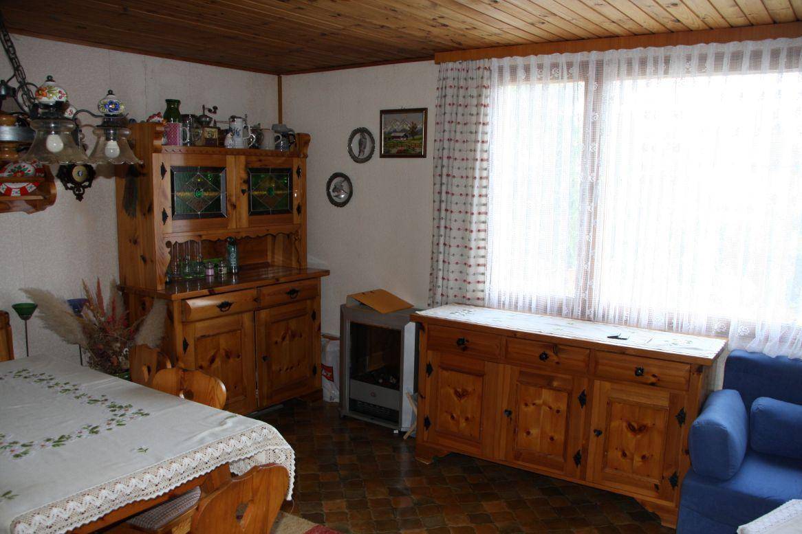 Kombinierter Wohn- und Essbereich mit Holzmöbeln, Holzdecke und großen Fenstern für viel Licht.