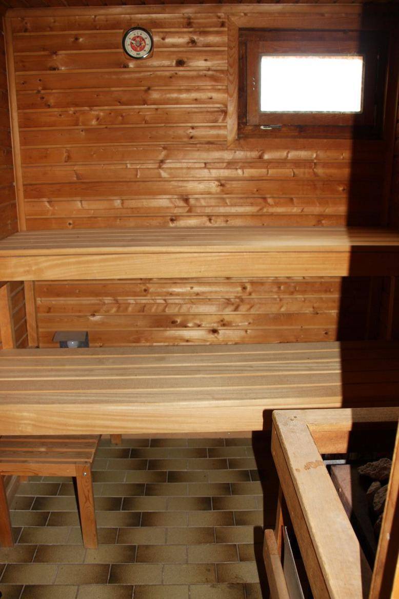 Holzvertäfelte Sauna mit zwei Bänken und kleinem Fenster für Entspannung.