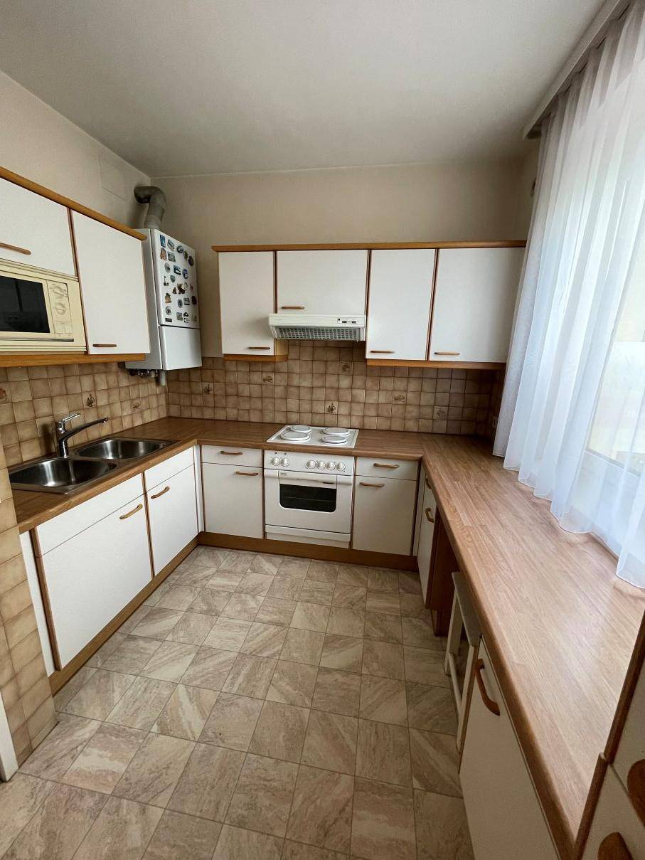 Funktionale Küche mit weißen Schränken, Holz-Arbeitsplatten und Fliesenboden.