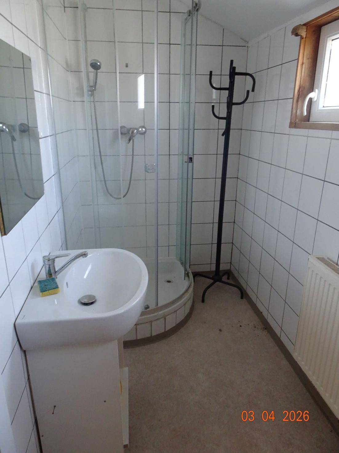 Badezimmer mit Duschkabine, Waschbecken und Fenster für natürliche Belüftung.