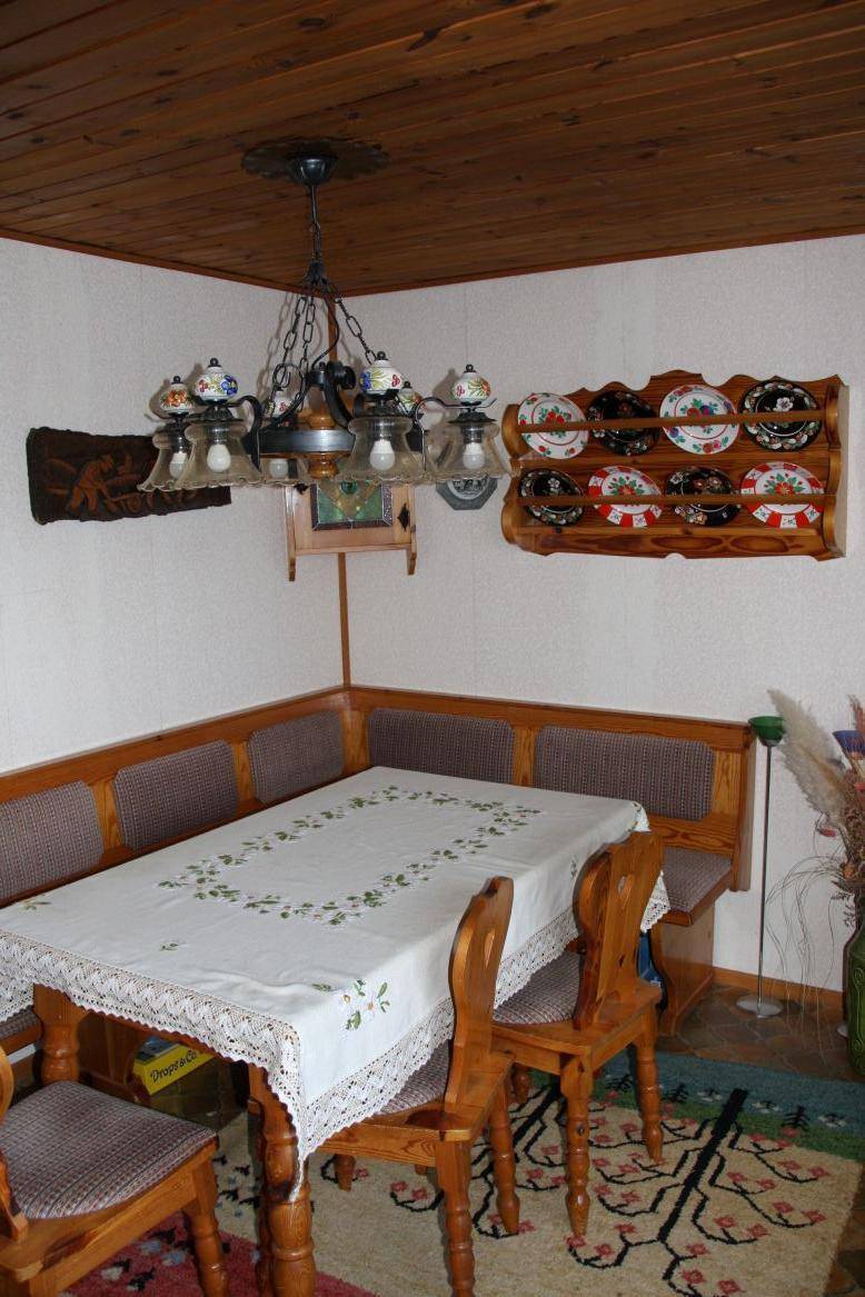 Traditioneller Essbereich mit Holztisch, Eckbank und Holzdecke in warmen Farbtönen.