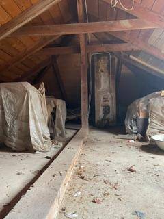 Unfertiger Dachboden mit sichtbaren Holzbalken und schrägen Holzdecken, ideal für zukünftige Ausbaupläne.