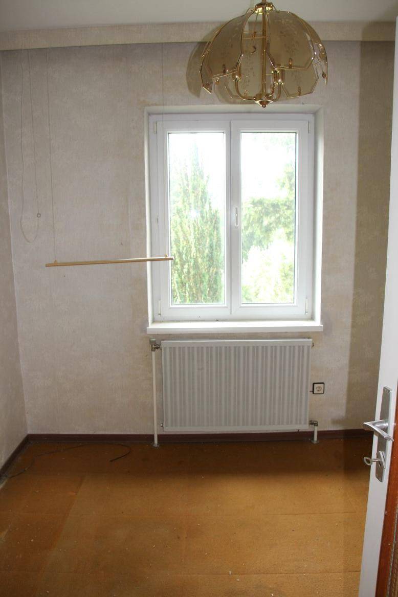 Helles Zimmer mit großem Fenster, Heizkörper und Blick ins Grüne, ideal als Schlafzimmer.