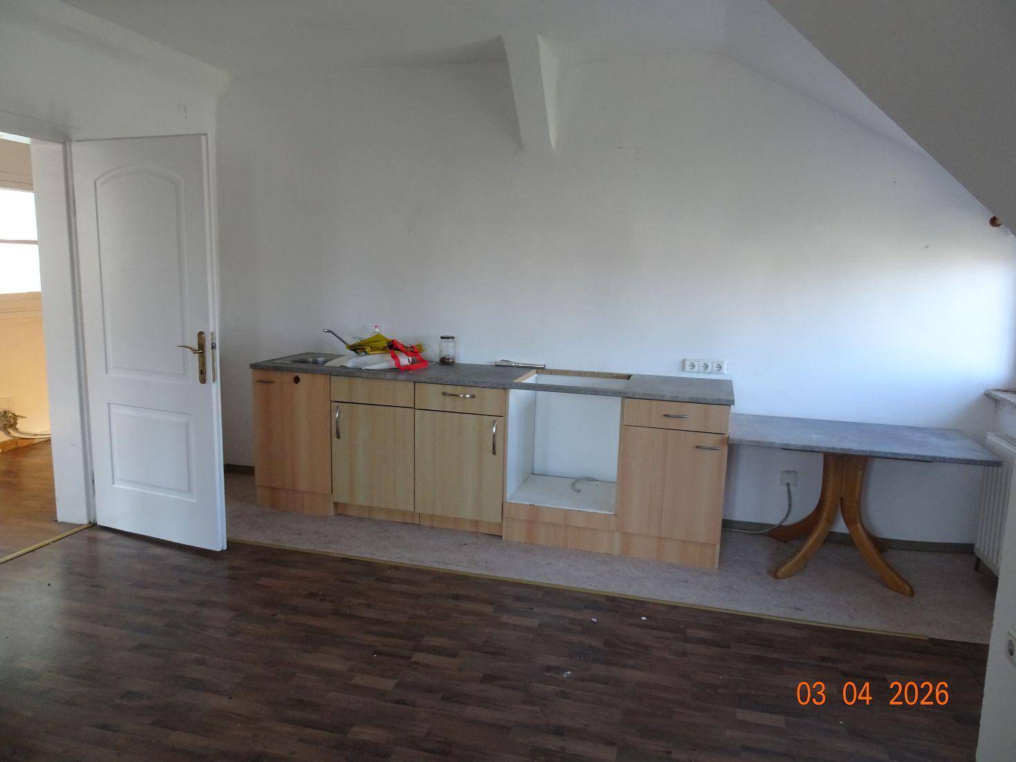 Raum mit kleiner Küchenzeile und Dachschräge, ideal für ein Studio-Apartment.