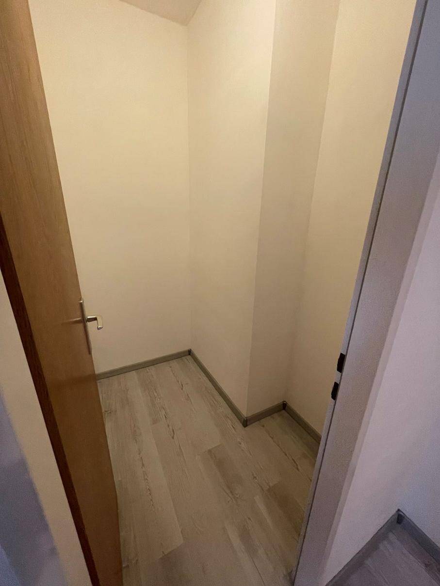 Kleiner Abstellraum mit hellem Laminatboden und weißen Wänden.