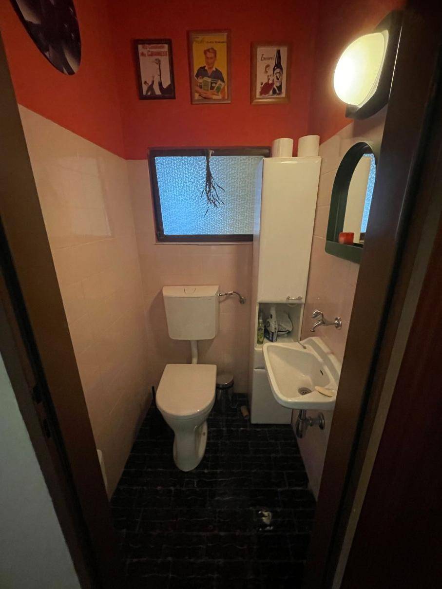 Kleines Gäste-WC mit Toilette, Waschbecken und Fenster in farbenfroher Gestaltung.