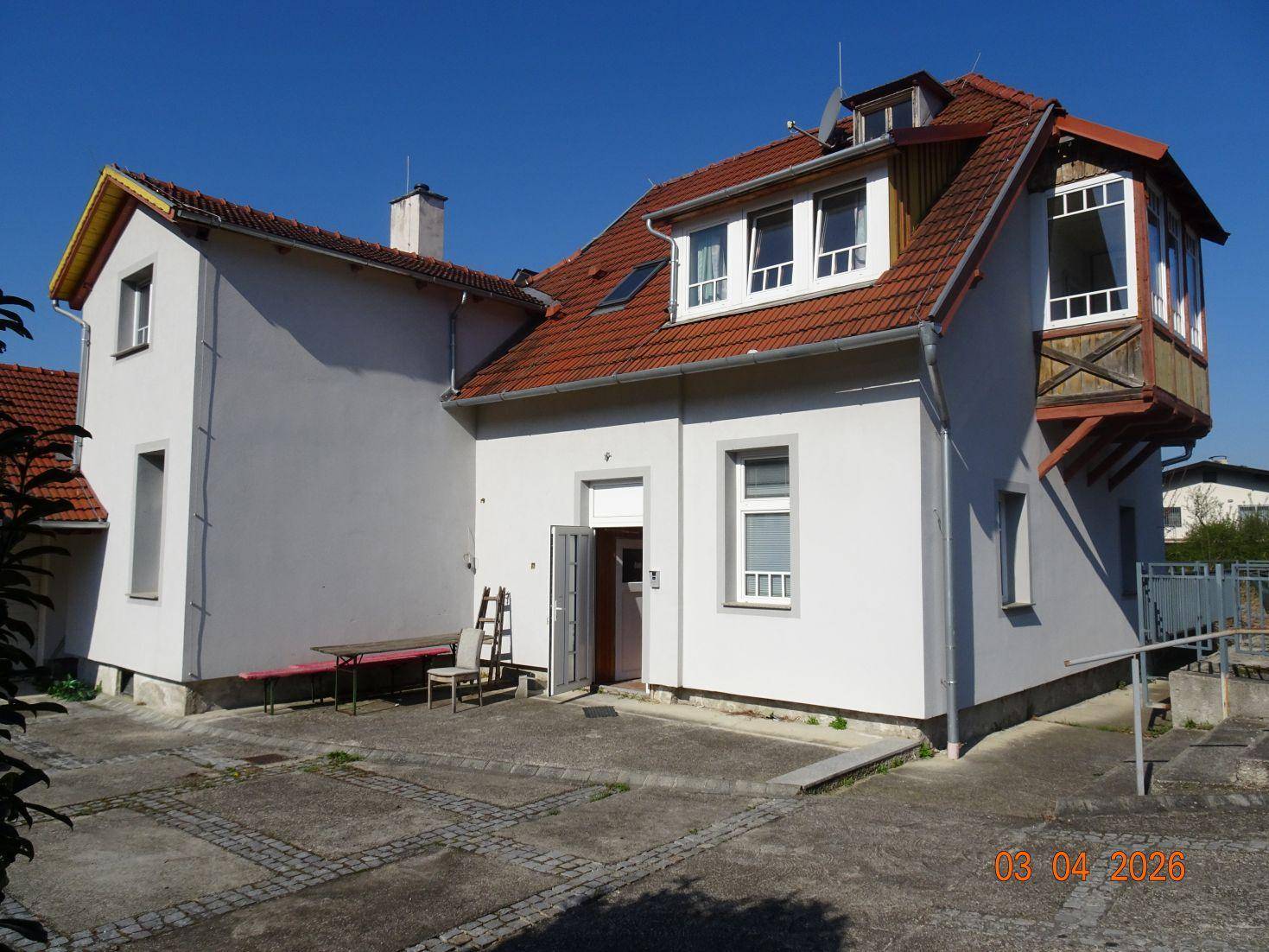 Hinterhofbereich mit gepflastertem Boden, Sitzgelegenheiten und Blick auf die Rückseite des Hauses.