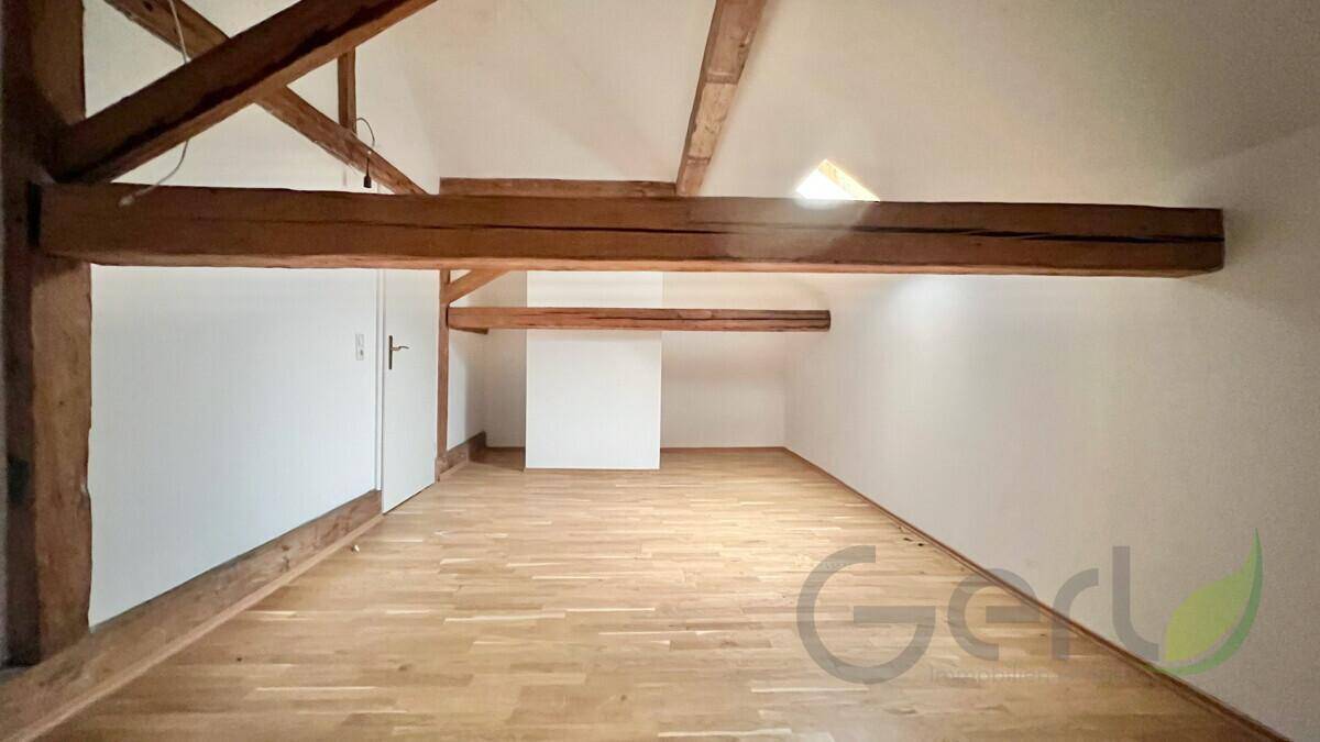 Ausgebauter Dachboden mit sichtbaren Holzbalken und Holzboden, ideal für zusätzlichen Wohnraum.