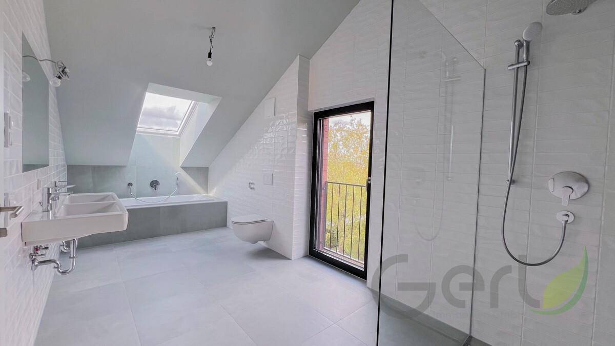 Modernes Badezimmer im Dachgeschoss mit Doppelwaschbecken, Badewanne, Dusche und Dachfenster.