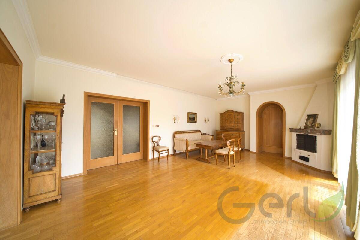 Geräumiges Wohnzimmer mit Parkettboden, Kamin und traditionellen Holzmöbeln.