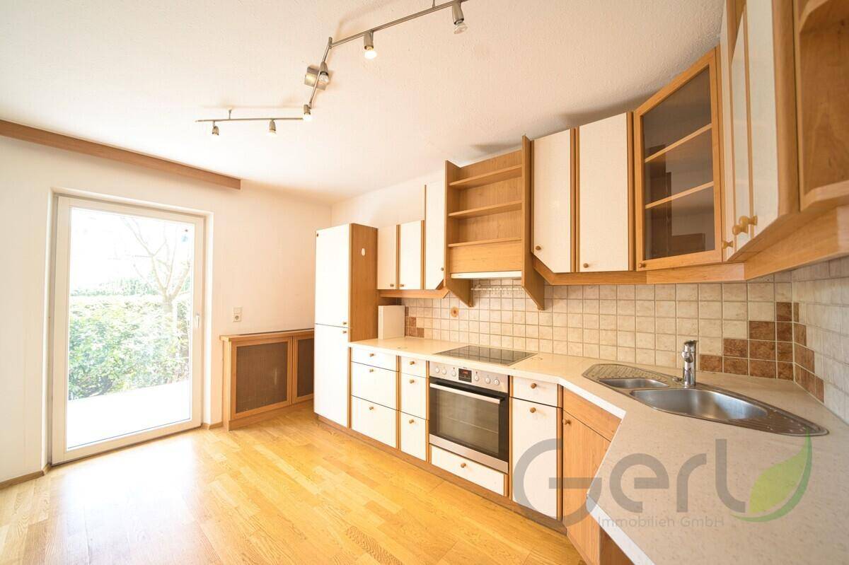 Einbauküche mit hellen Fronten, Holzdetails und Fenster zum Garten.