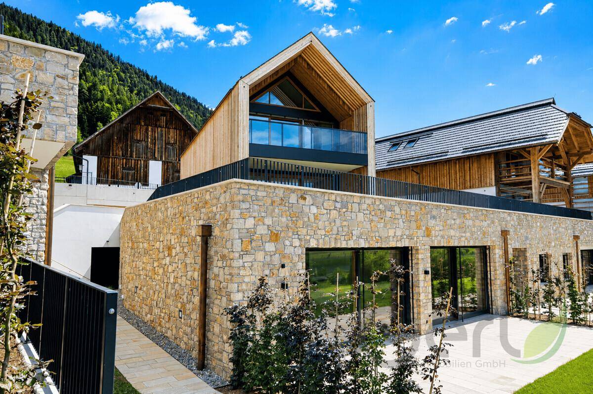 Beeindruckende moderne Villa mit Natursteinfassade und Holzdetails in alpiner Landschaft.