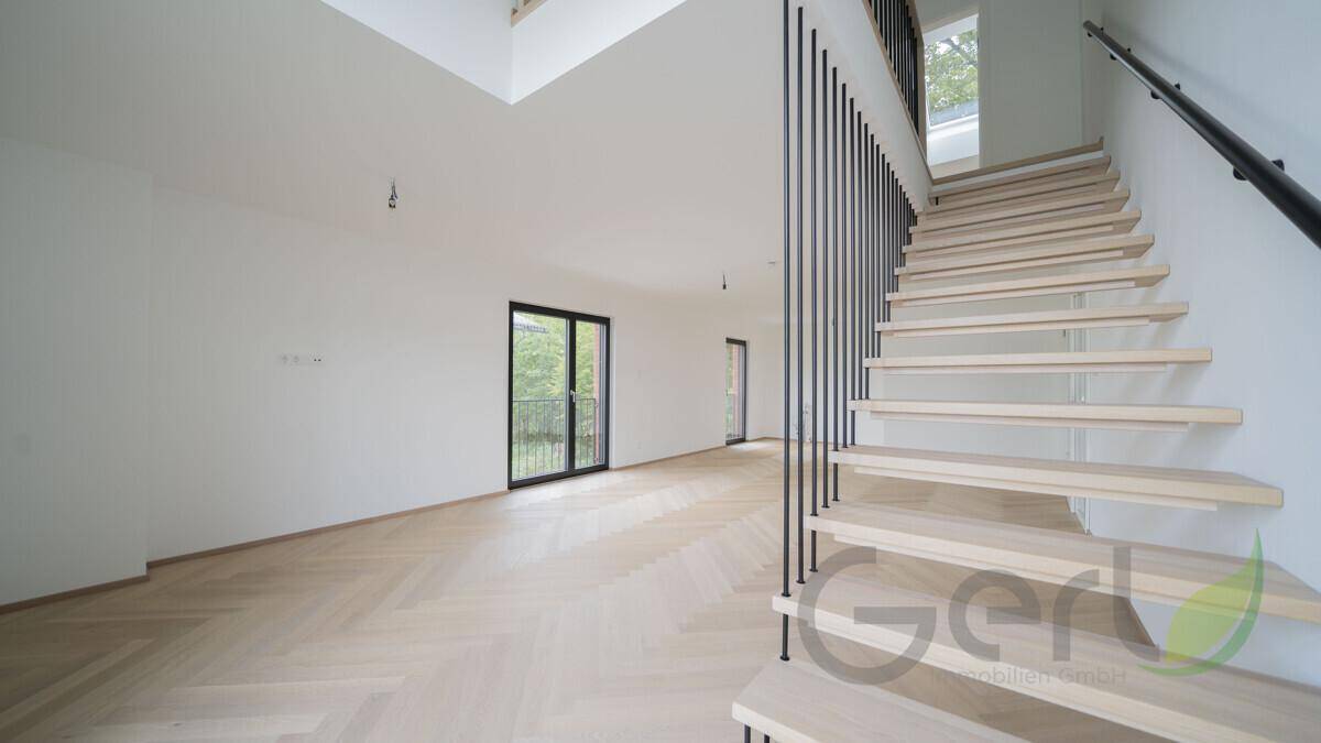 Heller, leerer Wohnraum mit Fischgrätparkett, hohen Decken und Zugang zum Balkon.