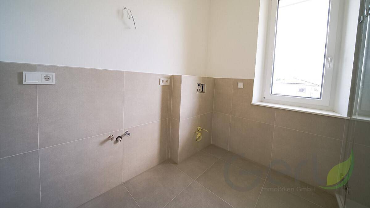 Unfertiges Badezimmer mit Fliesen an Wänden und Boden, bereit für die Installation der Sanitärobjekte.