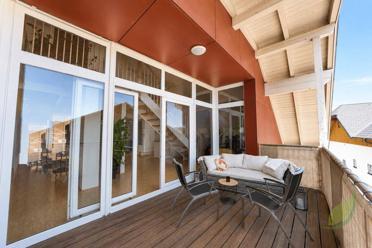 Geräumiger Balkon mit Sitzgelegenheiten und Blick in den hellen Innenbereich des Hauses.