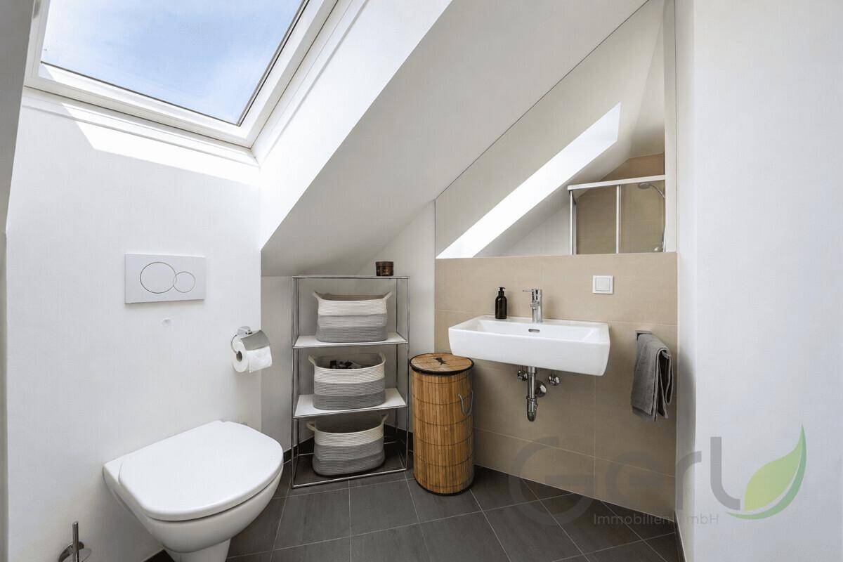 Kleines Gäste-WC mit Toilette, Waschbecken und einem Dachfenster für natürliches Licht.