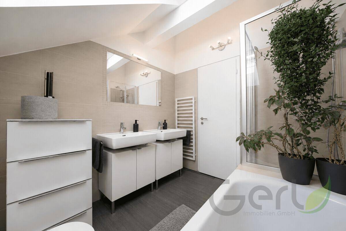 Modernes Badezimmer mit Doppelwaschbecken, Badewanne, Duschkabine und beigen Fliesen.