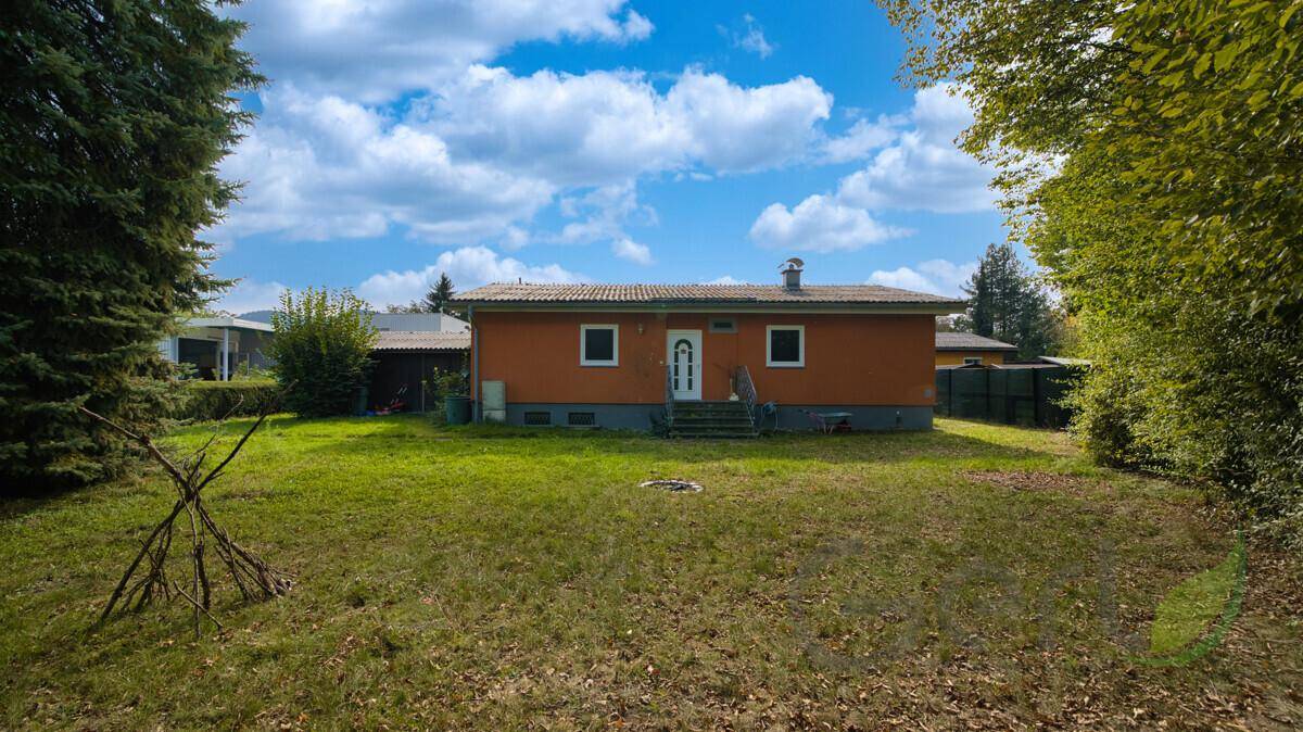 Rückansicht des Hauses mit orangefarbener Fassade und großem, gepflegten Gartenbereich.