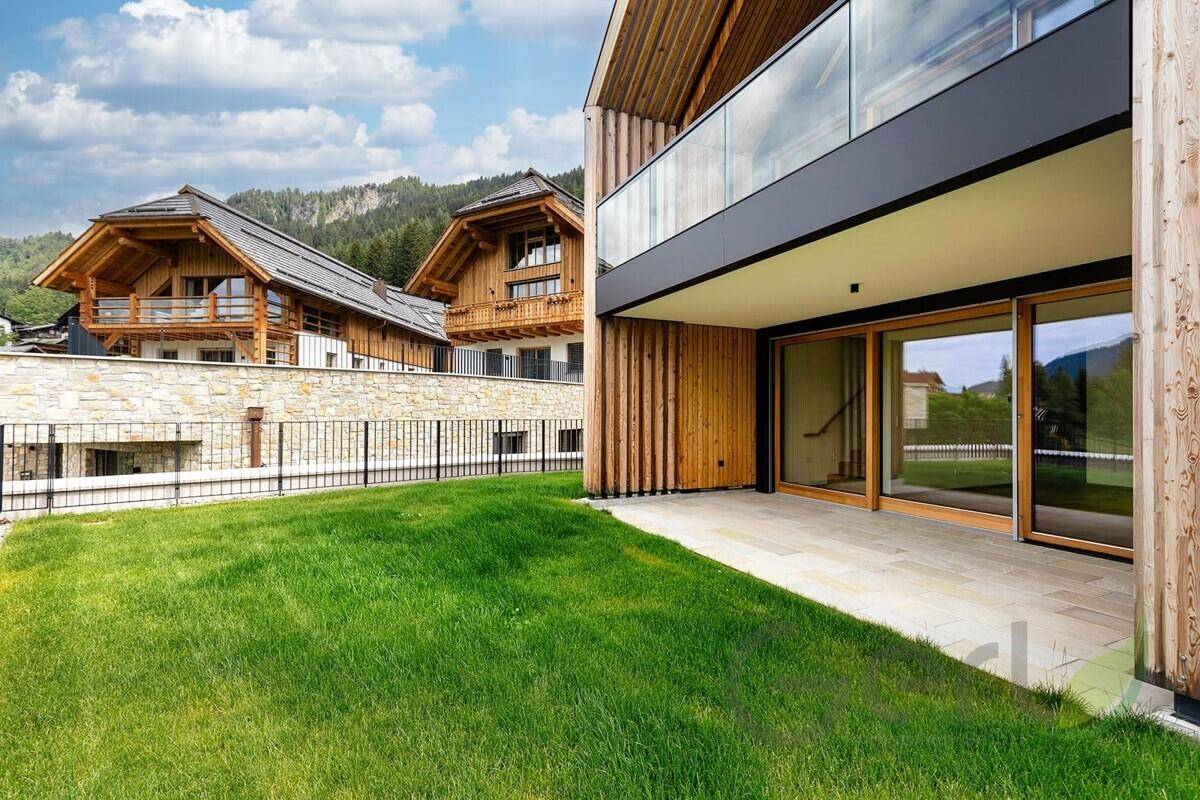 Gepflegter Rasenbereich neben der modernen Gebäudefassade mit Holzverkleidung und Terrasse.
