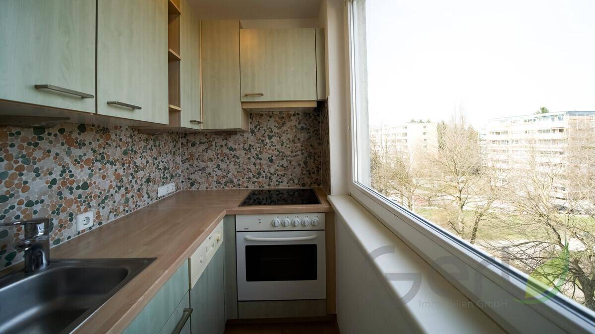 Kleine Küche mit Einbaugeräten, Arbeitsplatte aus Holz und Blick ins Grüne.