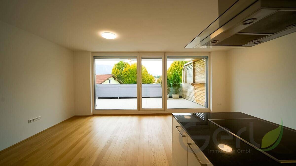 Geräumiger Wohn-Essbereich mit hellem Holzfußboden und großen Fenstern, die viel Tageslicht hereinlassen.