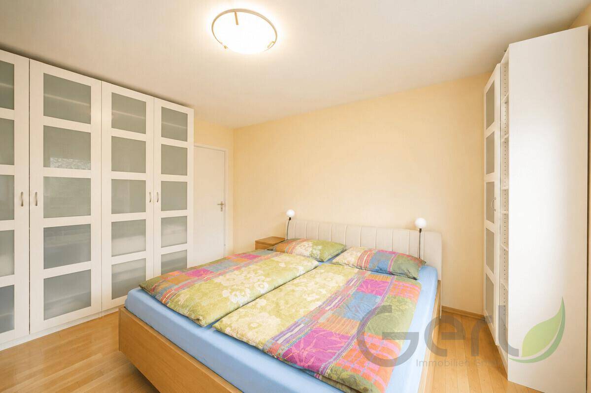 Helles Schlafzimmer mit Doppelbett und großen weißen Kleiderschränken mit Glasfronten.