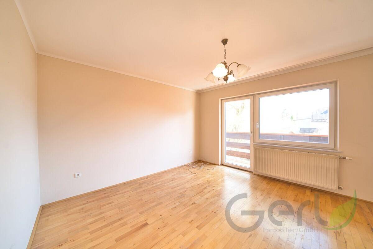 Geräumiges Zimmer mit Holzboden und Zugang zu einem Balkon.