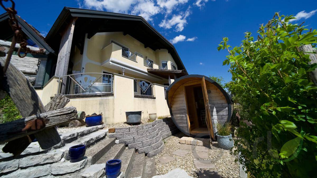 Außenansicht des Hauses mit einer einzigartigen Fasssauna im Gartenbereich und Steintreppe.