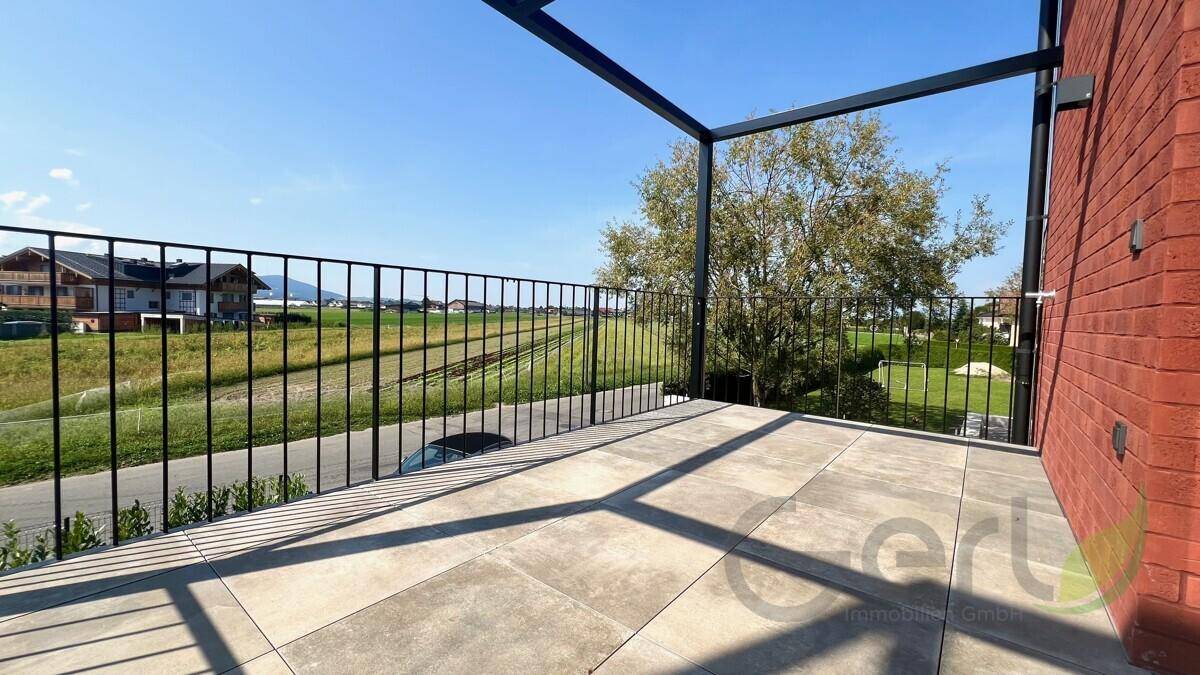 Geräumige Terrasse mit Fliesenboden und weitem Blick über die grüne Landschaft.