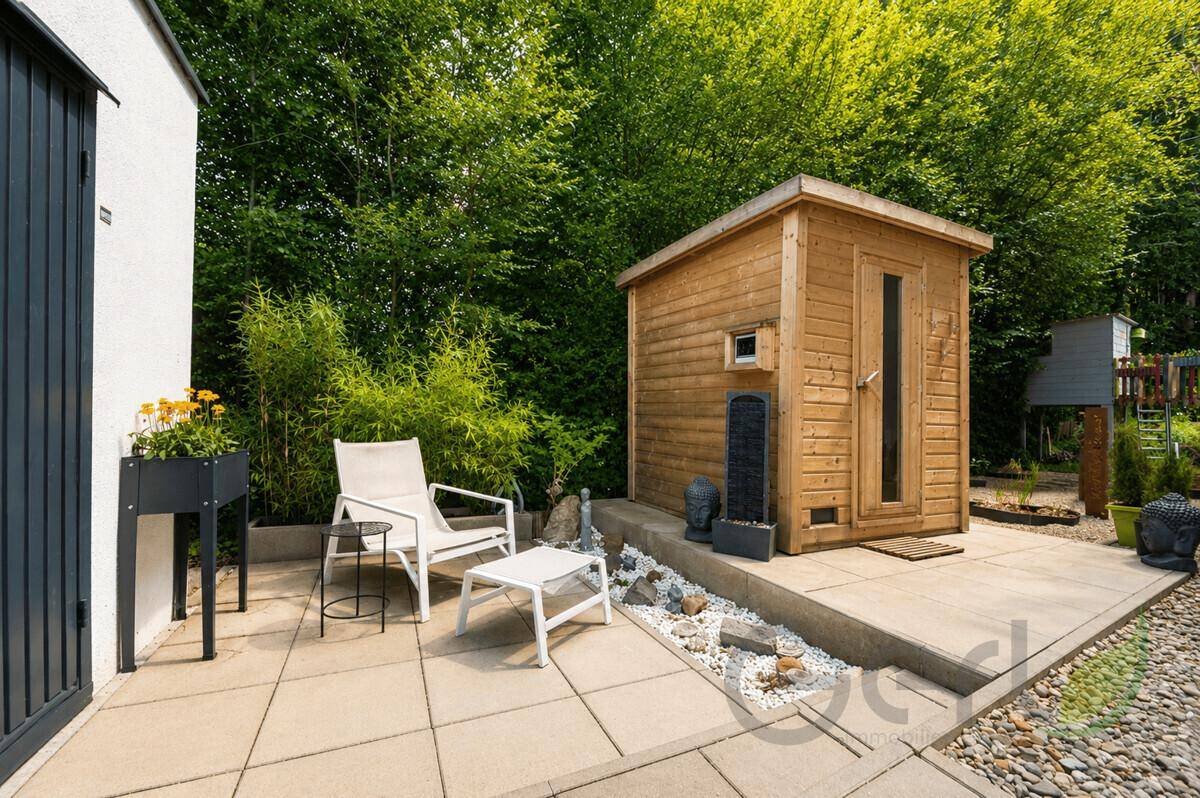 Außenbereich mit privater Sauna, gepflasterter Terrasse und umgebender Natur.