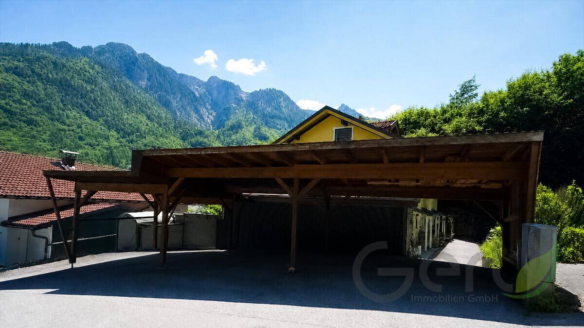 Geräumiger Holzcarport mit mehreren Stellplätzen vor einer beeindruckenden Bergkulisse.