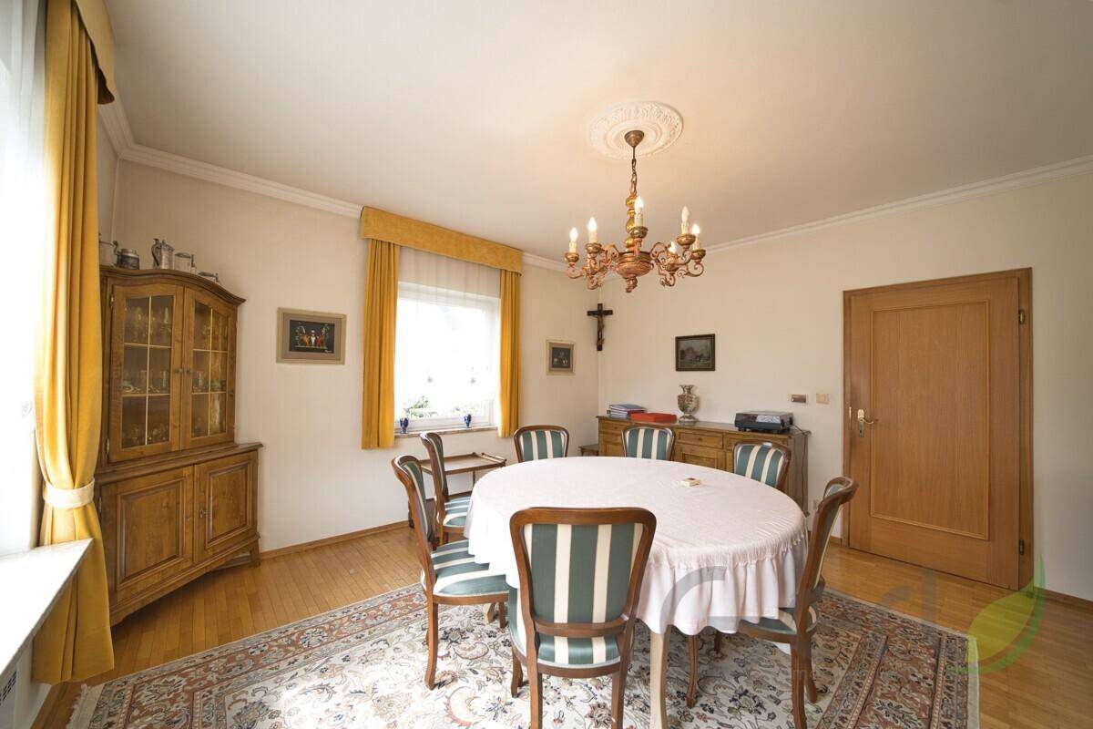 Gemütlicher Essbereich mit rundem Tisch, Holzmöbeln und einem Kronleuchter.