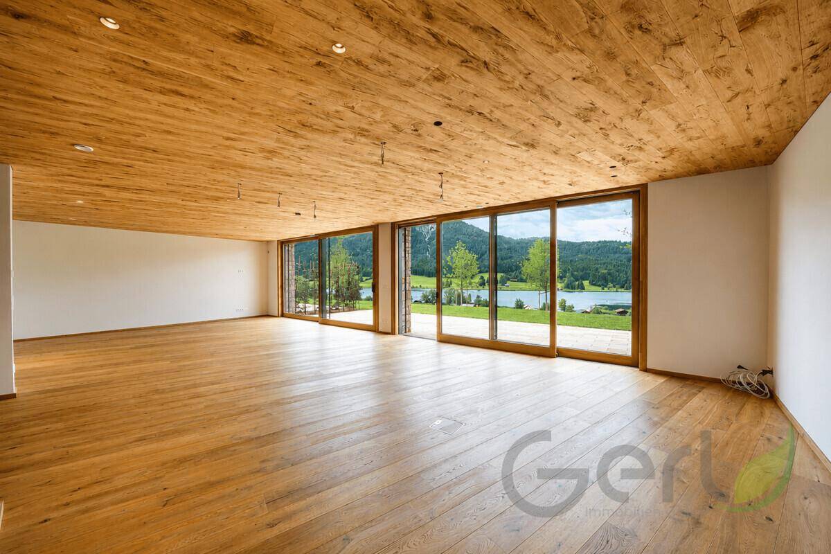 Geräumiger, heller Wohnbereich mit Holzboden und großen Schiebetüren zum See.