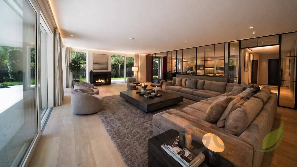 Geräumiges Wohnzimmer mit Kamin, Holzboden und großen Fensterfronten zum Garten.