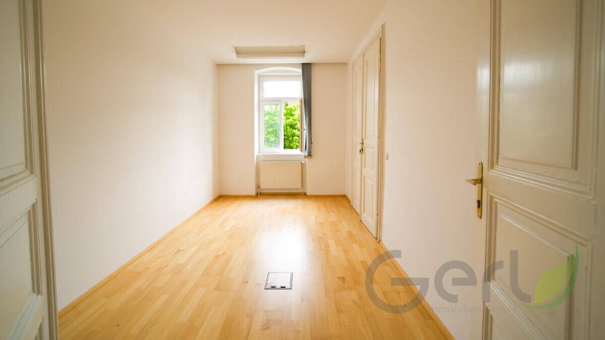 Funktionale Küche mit weißen Schränken, Holz-Arbeitsplatten und viel Tageslicht durch die Fenster.